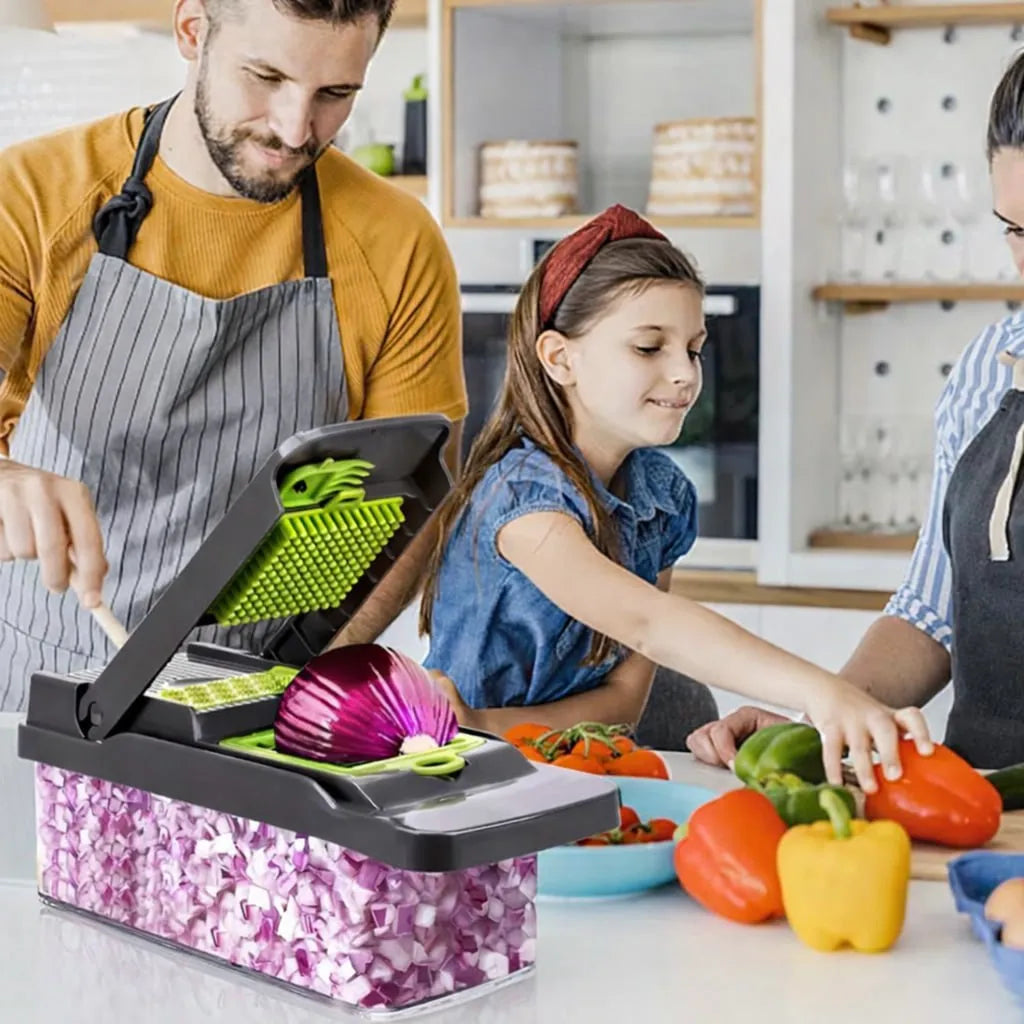 Family in a kitchen with a person using a vegetable chopper and children preparing vegetables.