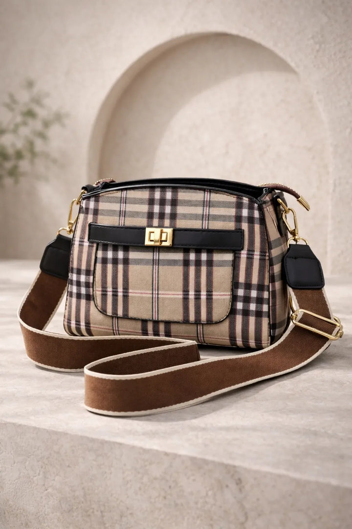 Plaid patterned handbag with brown strap on a light background