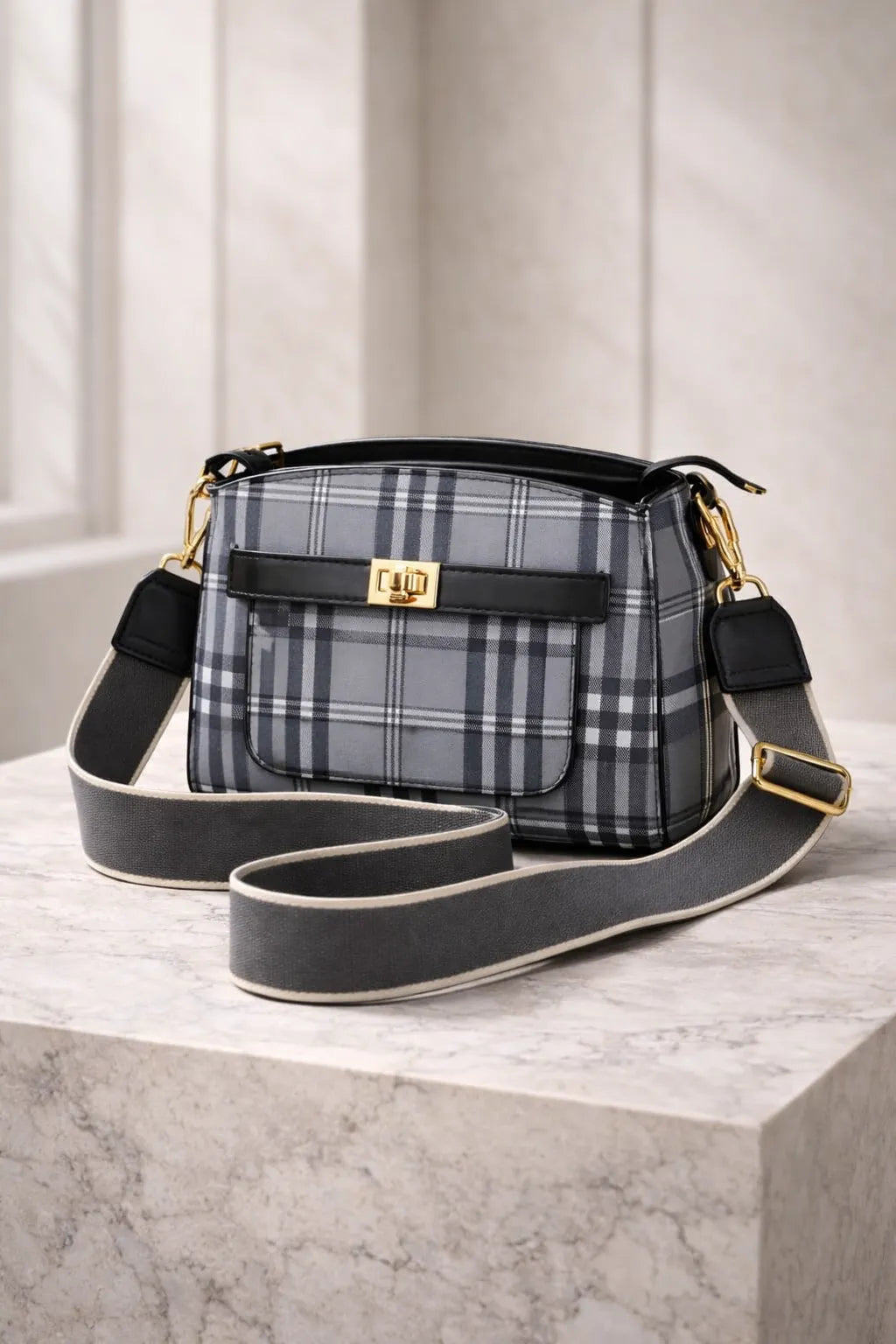 Plaid patterned handbag with gold accents on a marble surface