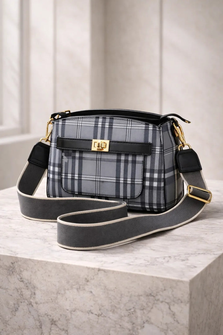 Plaid patterned handbag with gold accents on a marble surface