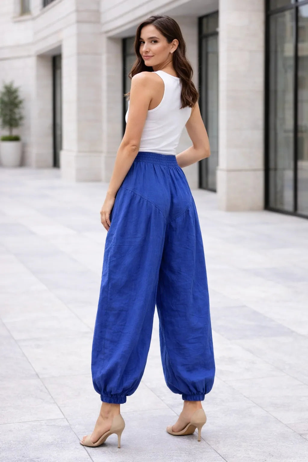 Woman wearing a white top and blue pants standing on a city street.
