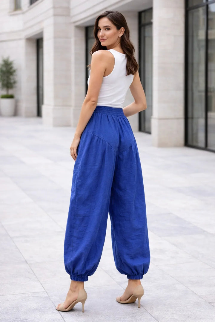 Woman wearing a white top and blue pants standing on a city street.