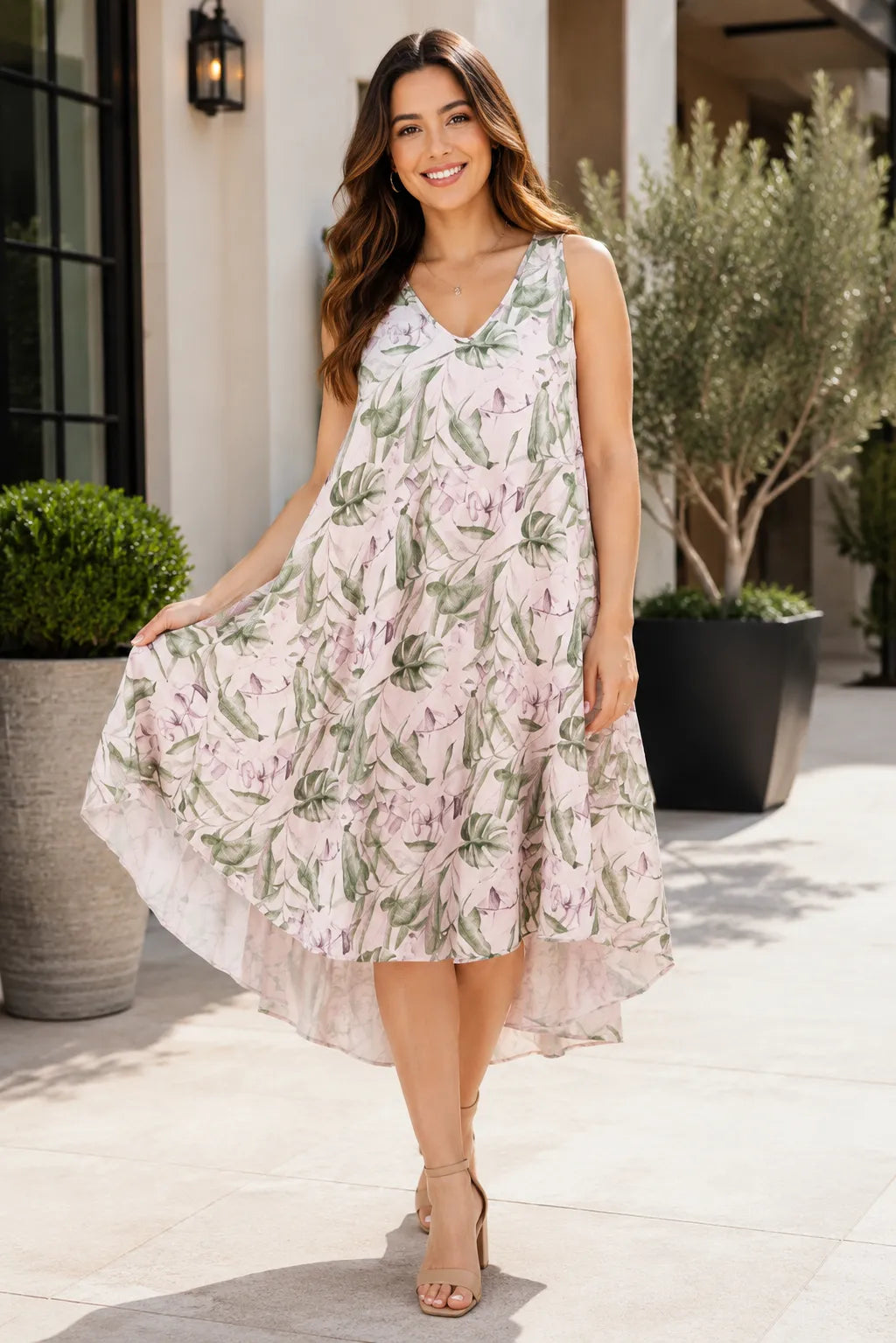 Model wearing a pale pink botanical leaf print sleeveless dip hem dress