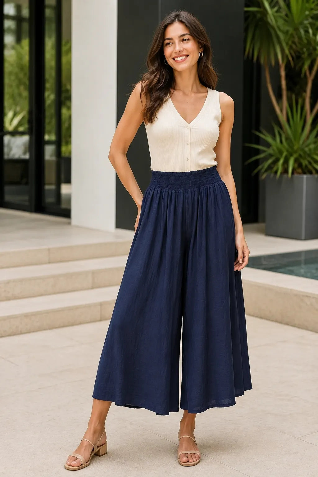 Woman wearing a cream top and navy wide-leg pants standing outdoors.