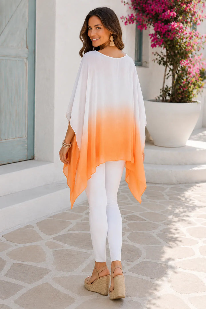Woman wearing a white and orange gradient dress with white leggings, standing on a stone path.